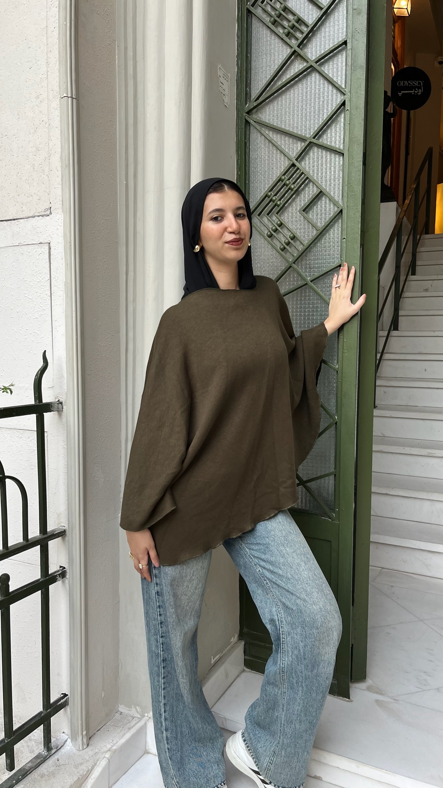 Olive Cape styled with light blue denim by a staircase