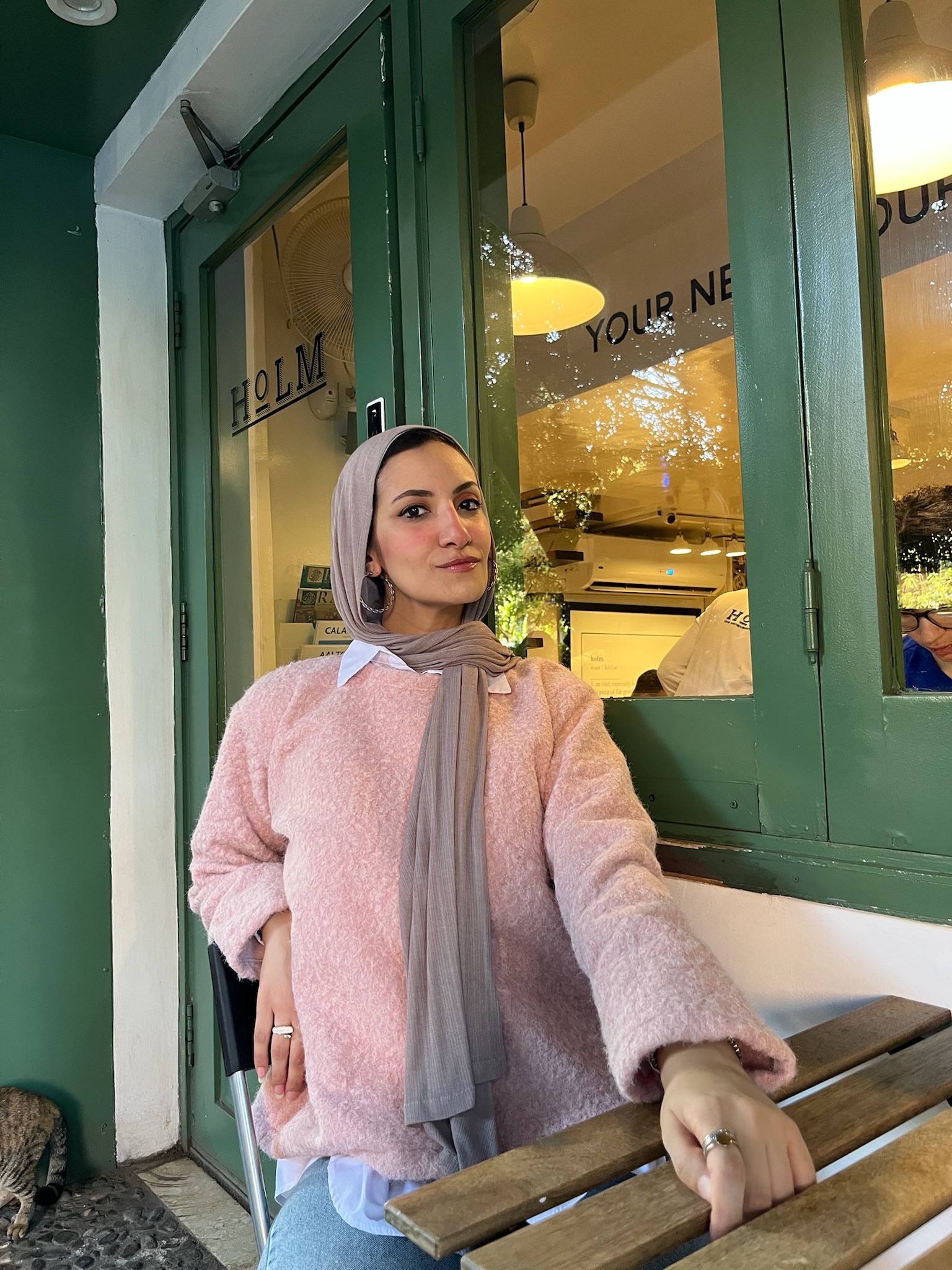 Pink Teddy Pullover styled with denim and a scarf outside a café